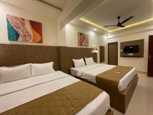 a hotel room with two beds and a flat screen tv at Yellow Sky in Baga