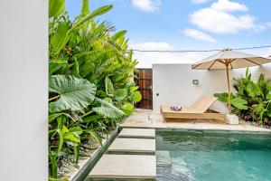 una piscina con panchina e ombrellone accanto a una casa di Elba Villa by Hombali a Canggu