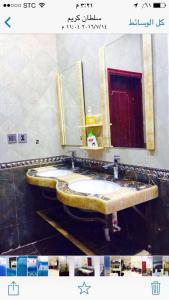 un bagno con due lavandini e un grande specchio di شاليه الراحة a Al Majmaah