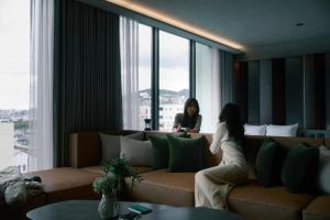 una mujer sentada en un sofá en una habitación de hotel en FAV LUX Nagasaki, en Nagasaki