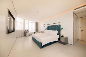 Schlafzimmer mit einem weißen Bett und einem TV in der Unterkunft Shanghai Autoongo Bund Hotel in Shanghai