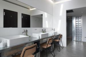 a bathroom with a long counter with sinks and chairs at 軟寓 nńg inn in Tainan