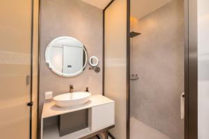 ein Bad mit einem Waschbecken und einem Spiegel in der Unterkunft Shanghai Autoongo Bund Hotel in Shanghai