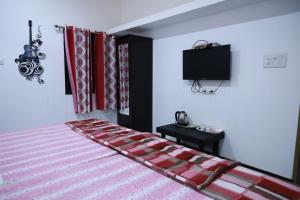 a bedroom with a bed with a tv on the wall at HOMESTAY ( EAGLE NEST ) in Bhuj