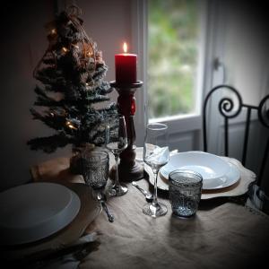 シラクーサにあるacquarelloのキャンドルとワイングラスとクリスマスの木が並ぶテーブル