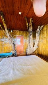1 dormitorio con 1 cama con un árbol en la pared en Meraki Tribe Heritage, en Munnar