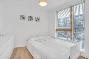 a white bedroom with a bed and a window at Spacious 2 bedroom apartment with balcony in London