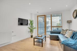 a living room with a blue couch and a table at Spacious 2 bedroom apartment with balcony in London