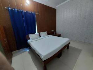 Dormitorio pequeño con cama con cortina azul en Saukari Palace, en Dehradun