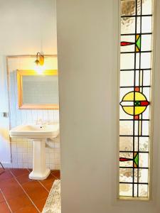 ein Badezimmer mit einem Waschbecken und einem Buntglasfenster in der Unterkunft Hagakure in Calcata