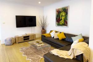 a living room with a couch and a flat screen tv at On The Esplanade - Close to beach & Cronulla mall with Aircon in Cronulla