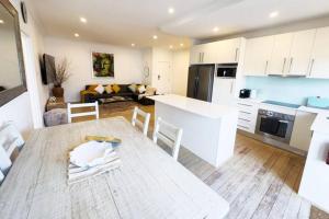 cocina y sala de estar con mesa de madera en una habitación en On The Esplanade - Close to beach & Cronulla mall with Aircon en Cronulla