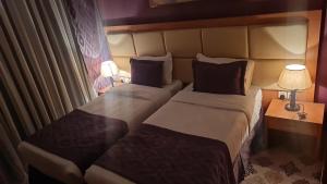une chambre d'hôtel avec 2 lits et 2 lampes dans l'établissement شقق فندقية التلال, à La Mecque