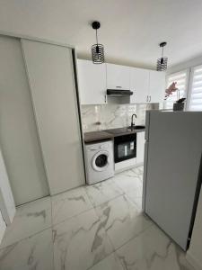 uma cozinha branca com um fogão e um micro-ondas em Appartement 2 pieces, salon et chambre, 44m2 refait à neuf em Clichy