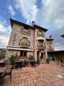 a brick building with tables and chairs in front of it at Hotel Ambassador Voskopojë in Voskopojë