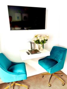 dos sillas azules junto a un escritorio con un jarrón de flores en The Villa Rosa Guest House & Self-catering Apartments, en Ciudad del Cabo