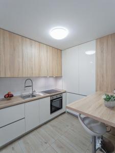 a kitchen with white cabinets and a sink and a counter at Apartman Franko - SELF CHECK IN in Osijek