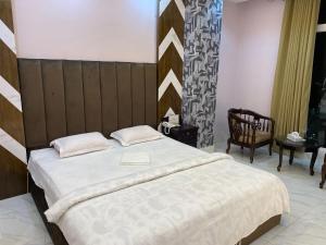 ein Schlafzimmer mit einem großen Bett und einem Stuhl in der Unterkunft Hotel Grand Akther Sylhet in Sylhet