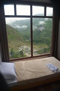 a bed in a room with a large window at Batad Roberto's Abung Inn and Restaurant in Banaue