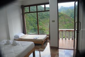 een kamer met 2 bedden en een groot raam bij Batad Roberto's Abung Inn and Restaurant in Banaue