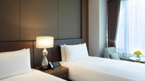 a hotel room with two beds and a table with a lamp at LOTTE City Hotel Gimpo Airport in Seoul