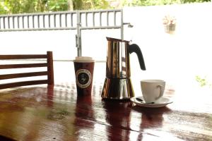 una macchinetta del caffè e tazze su un tavolo di legno di MENAKA HOMESTAY a Tangalle