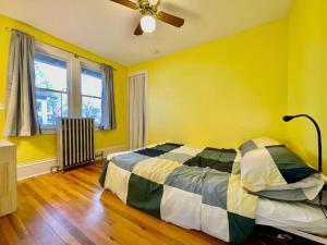 een gele slaapkamer met een bed en een plafondventilator bij Historic Home Near Minnehaha Falls in Minneapolis