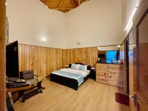 a bedroom with a bed and a desk and a television at Shri Shail Inn Mukteshwar in Mukteshwar