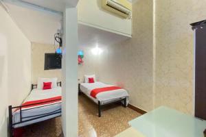 1 Schlafzimmer mit 2 Betten und einem TV in der Unterkunft RedDoorz Syariah at Prapen Jaya Surabaya in Surabaya