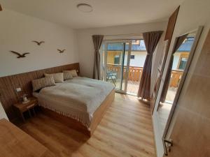 1 dormitorio con 1 cama y balcón en Apartmány - Malé Lipno en Černá v Pošumaví