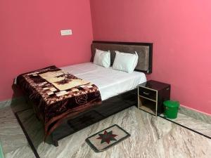 a bedroom with a bed with a pink wall at Indiana home stay in Khajurāho