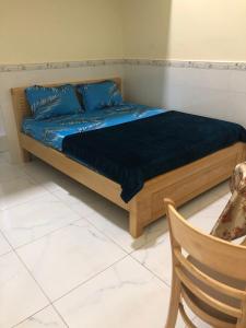 un letto con cuscini blu e una sedia in una stanza di Nhà Nghỉ Bảo Ngọc a Tché Réou