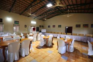 einen Bankettsaal mit Tischen und weißen Stühlen in der Unterkunft Nisarga Resort in Kaglipur