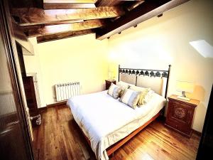 una camera da letto con letto, lenzuola bianche e pavimenti in legno di Ático duplex a pie de pistas de esquí a La Molina