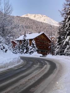 a log cabin with a snow covered roof on a road at Colorado Riders Chalet in Crans-Montana