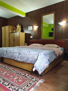 - une chambre avec un lit, un miroir et un tapis dans l'établissement Azalea Holidays On Mall, à Darjeeling