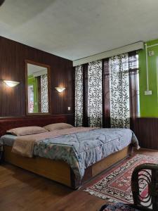 - une chambre avec un grand lit et un miroir dans l'établissement Azalea Holidays On Mall, à Darjeeling