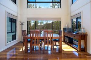 a dining room with a table and chairs and windows at Easygoing Poolside Relaxation on Wyong River in Tuggerah