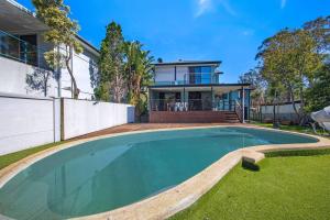 a swimming pool in front of a house at Easygoing Poolside Relaxation on Wyong River in Tuggerah
