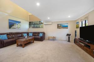 a living room with a couch and a flat screen tv at Easygoing Poolside Relaxation on Wyong River in Tuggerah