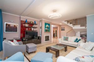 een woonkamer met witte meubels en een televisie bij Villa Laperosa in Cavtat