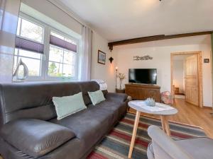 a living room with a leather couch and a tv at Appartement Huus Appelboom in Nordstrand