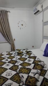 1 dormitorio con 1 cama con reloj en la pared en WHITE EMIRATES HOTEL AND APARTMENT, en Akinde