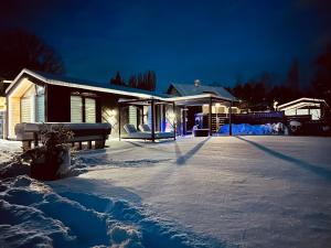 uma casa coberta de neve com um banco à sua frente em Voralpen Lodge - Ferienhaus mit Gym & Wellnessbereich em Traisen