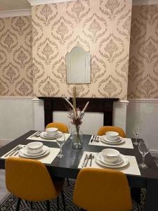 een eettafel met gele stoelen en een tafel met borden en glazen bij Cedar Lodge in Walton on the Hill