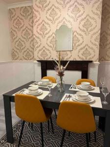 a dining room table with yellow chairs and a table with plates at Cedar Lodge in Walton on the Hill