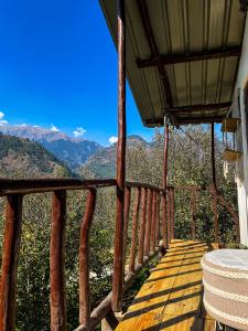 a wooden balcony with a view of the mountains at MANDAP COTTAGE & CAFE in Nagar