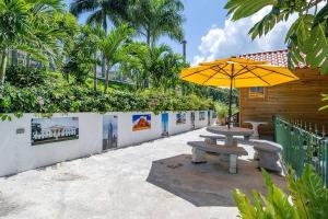 einen Picknicktisch mit gelbem Regenschirm neben einem Zaun in der Unterkunft Private Tiny House w/ Pool in Montego Bay