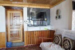 a room with a door and a couch and a television at Kin Vatika Homestay in Kalpa