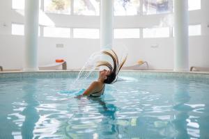 a woman in a swimming pool with a water hose at Hotel Terme Marine Leopoldo II TERME & SPA in Marina di Grosseto